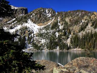 обои Гора у озера с редкими елями и снегом фото