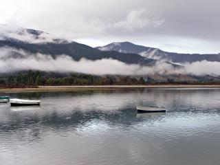 обои Озеро с лодками возле гор с облаками фото