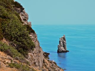 обои Высокий скалистый берег и маленькая скалa в море фото