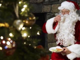 обои Санта-Клаус пьющий молоко с печеньем на фоне елки фото