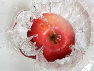 обои Красное полосатое яблоко,  падающее в прозрачную воду фото