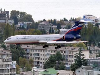 обои Ту-154М низко летит над морским городком фото
