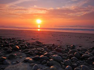 обои Красивый закат и камни на песке фото