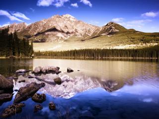 обои Чистое озеро с камнями у гор с хвойным лесом фото